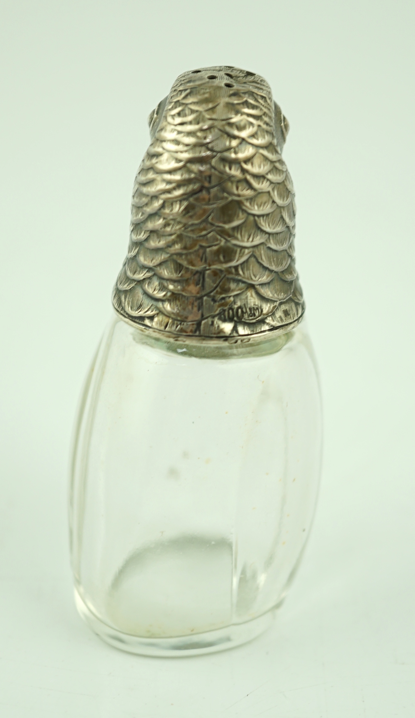 An early 20th century German 800 standard silver mounted glass pepperette, the cover modelled as the head of a parrot